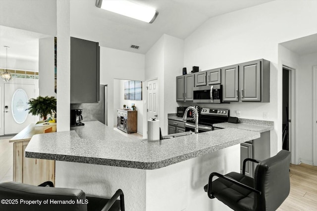 kitchen featuring kitchen peninsula, gray cabinets, stainless steel appliances, and a breakfast bar