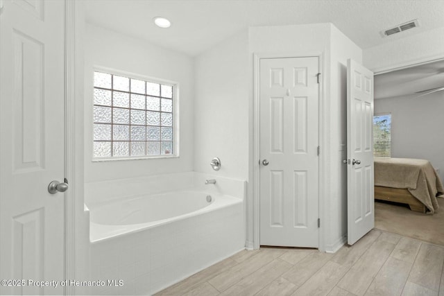 bathroom featuring hardwood / wood-style flooring and tiled tub