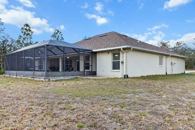 back of property featuring a lawn and glass enclosure