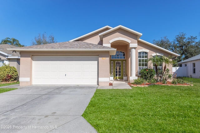 view of front of property with an attached garage, concrete driveway, a front yard, and stucco siding