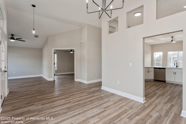 interior space with sink, high vaulted ceiling, an inviting chandelier, and light hardwood / wood-style floors