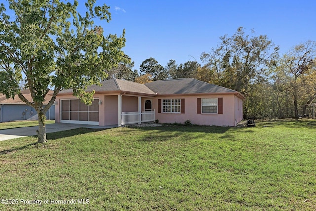 ranch-style home featuring driveway, an attached garage, a sunroom, stucco siding, and a front lawn