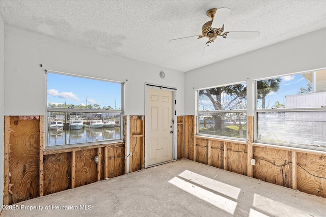 spare room featuring a water view, plenty of natural light, and a textured ceiling