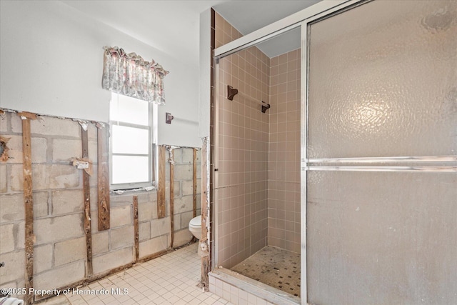 bathroom with tile patterned floors, tile walls, toilet, and a shower with door