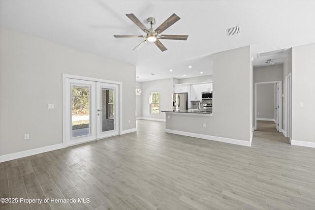 unfurnished living room with sink, french doors, light wood-type flooring, and ceiling fan