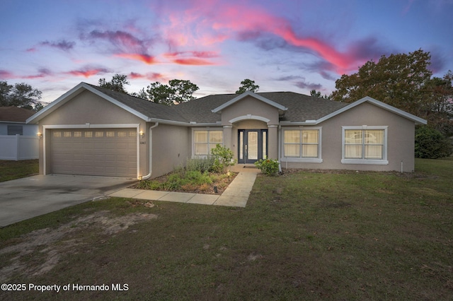 ranch-style home featuring stucco siding, driveway, roof with shingles, a front yard, and a garage