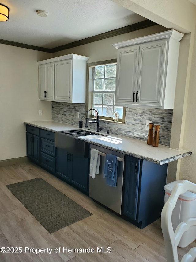 kitchen featuring tasteful backsplash, white cabinetry, stainless steel dishwasher, crown molding, and light hardwood / wood-style flooring