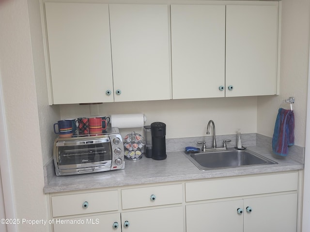 kitchen featuring light countertops, a sink, white cabinetry, and a toaster