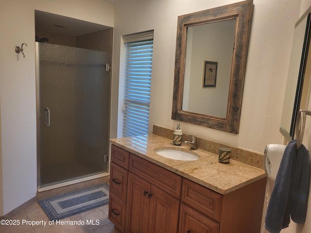 bathroom with tile patterned flooring, vanity, and a shower stall