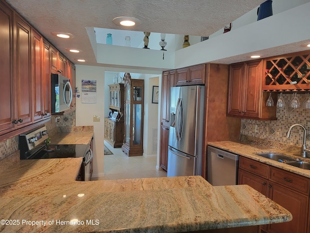 kitchen featuring appliances with stainless steel finishes, a sink, backsplash, and a textured ceiling