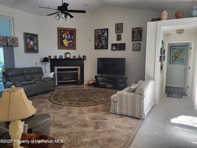 living room with vaulted ceiling, a ceiling fan, and a glass covered fireplace