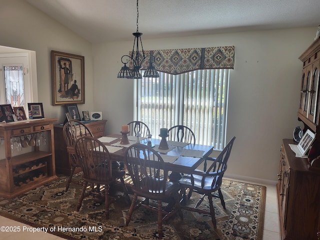 dining area with vaulted ceiling, a textured ceiling, baseboards, and tile patterned floors