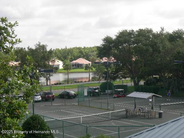 view of sport court with a water view and fence