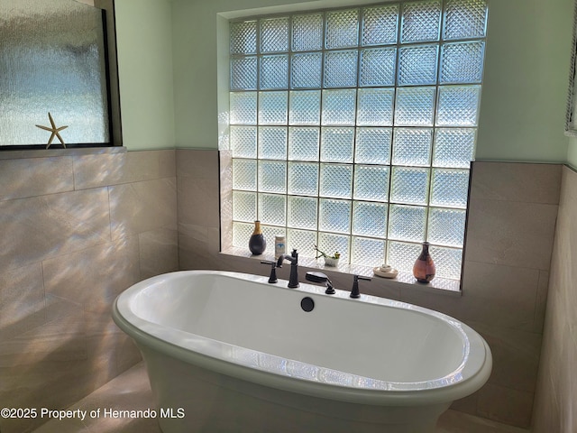 full bathroom featuring a soaking tub and tile walls