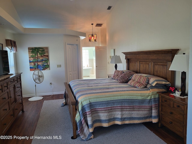 bedroom featuring ensuite bathroom, dark wood finished floors, visible vents, and baseboards