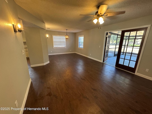 empty room with dark hardwood / wood-style flooring, ceiling fan, and a textured ceiling