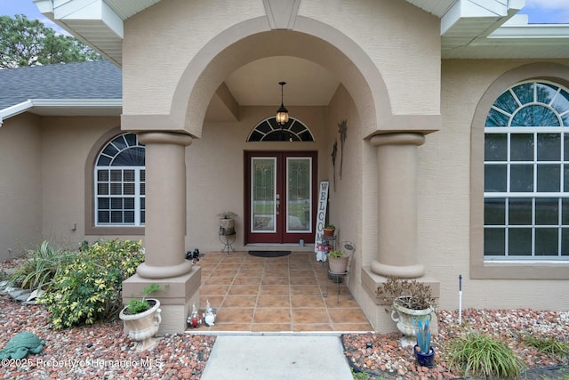 property entrance featuring a shingled roof, french doors, and stucco siding