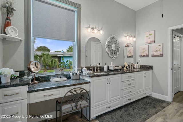 full bath featuring wood finished floors, a sink, baseboards, and double vanity