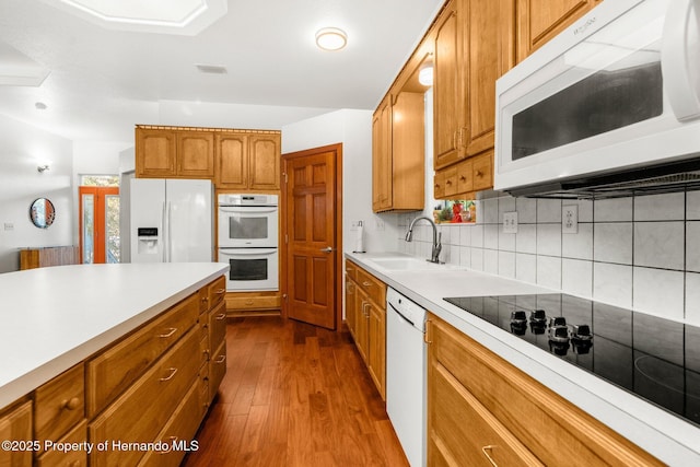 kitchen featuring light countertops, white appliances, and brown cabinets