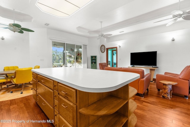 kitchen with brown cabinets, a kitchen island, open floor plan, and light countertops