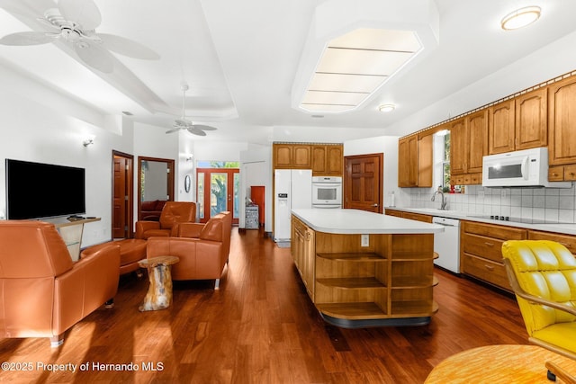 kitchen with white appliances, a center island, open floor plan, light countertops, and brown cabinets