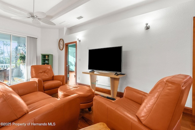 living area with a ceiling fan, baseboards, visible vents, and wood finished floors