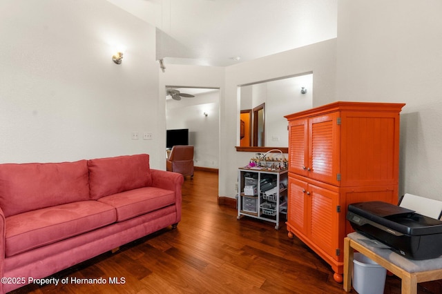 living room featuring dark wood-type flooring, a ceiling fan, and baseboards