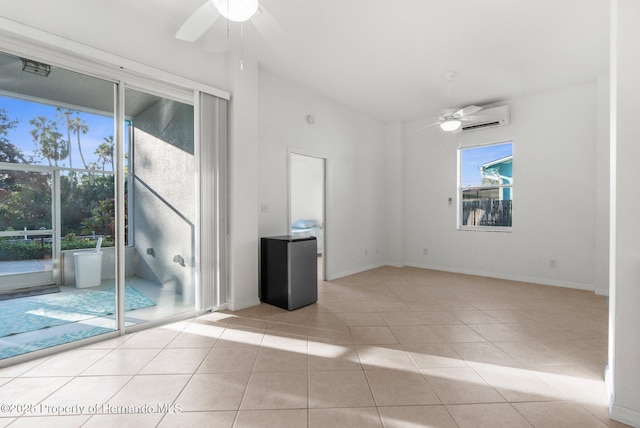 spare room with a wall unit AC, light tile patterned floors, lofted ceiling, a ceiling fan, and baseboards