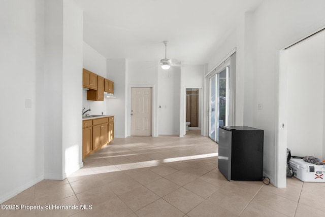 kitchen with light tile patterned floors, light countertops, freestanding refrigerator, and a ceiling fan