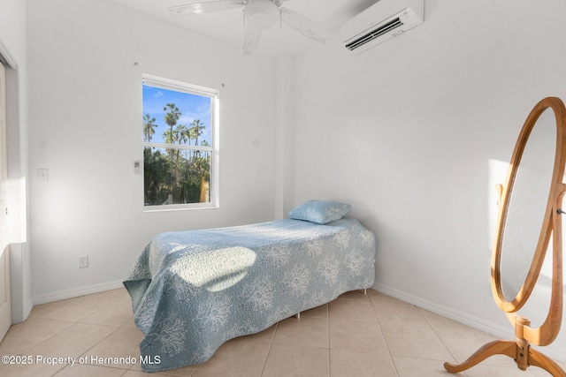 bedroom with a ceiling fan, an AC wall unit, baseboards, and light tile patterned floors