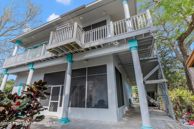 exterior space featuring a balcony, a sunroom, and stucco siding