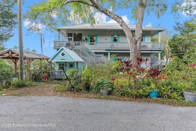 view of front of property featuring covered porch, metal roof, a standing seam roof, and stairs