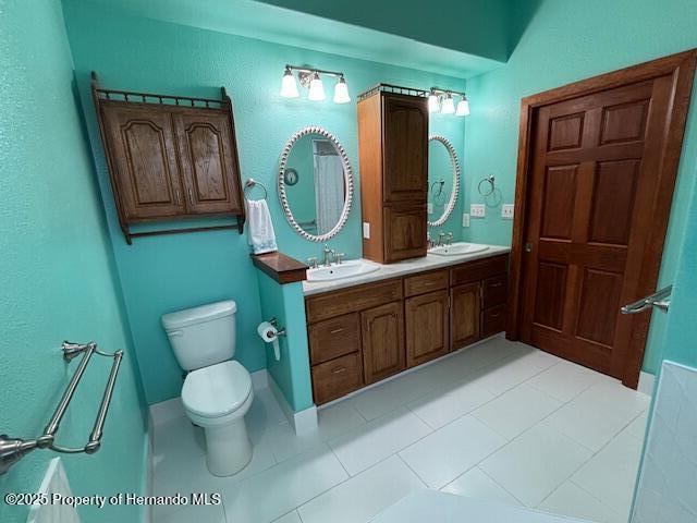 bathroom featuring tile patterned floors, a sink, toilet, and double vanity