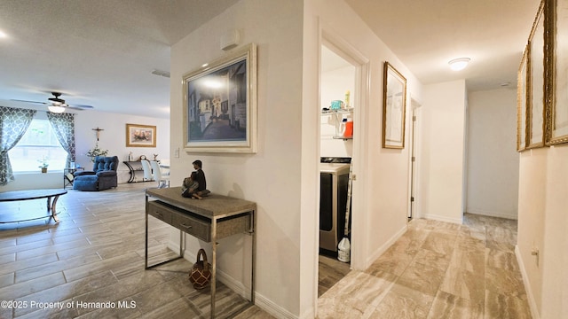 corridor with washer / dryer, light wood finished floors, and baseboards