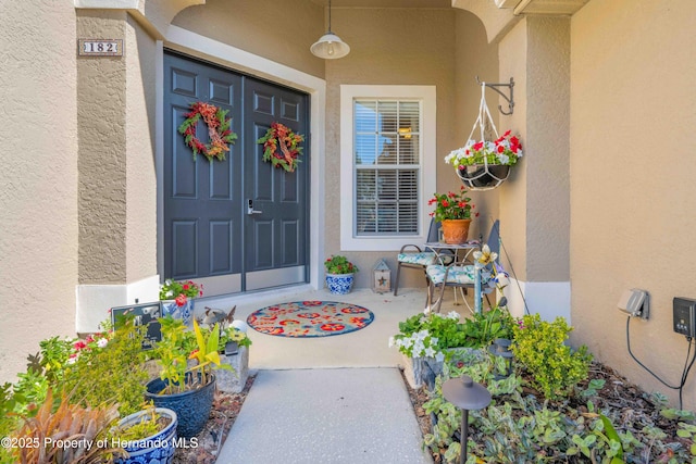 view of exterior entry with covered porch and stucco siding