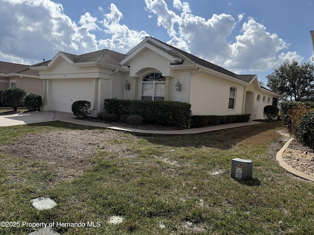 ranch-style home featuring a garage, a front yard, concrete driveway, and stucco siding