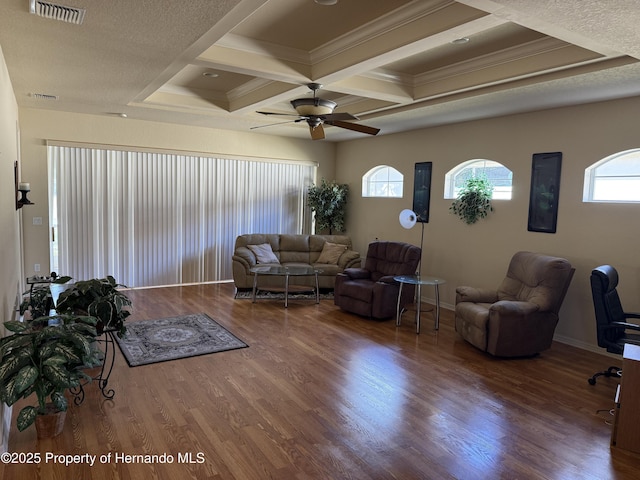 living area with coffered ceiling, wood finished floors, visible vents, and baseboards