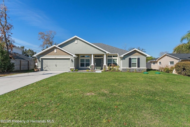 view of front of property featuring a front yard, fence, a garage, stone siding, and driveway