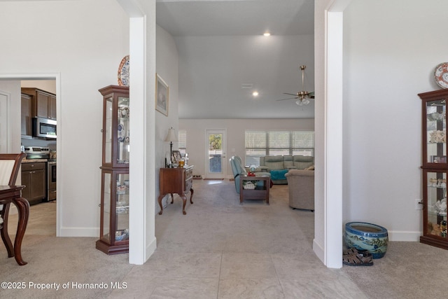 interior space featuring baseboards, high vaulted ceiling, and light colored carpet