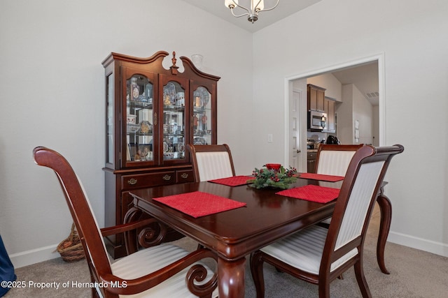 dining room with carpet floors, baseboards, and a notable chandelier