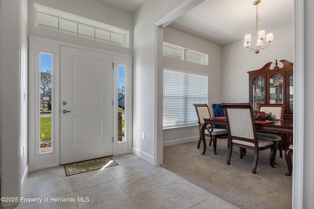 foyer entrance with plenty of natural light, light tile patterned floors, an inviting chandelier, and light colored carpet