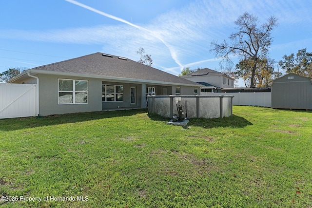 back of house featuring a yard, a storage unit, and fence