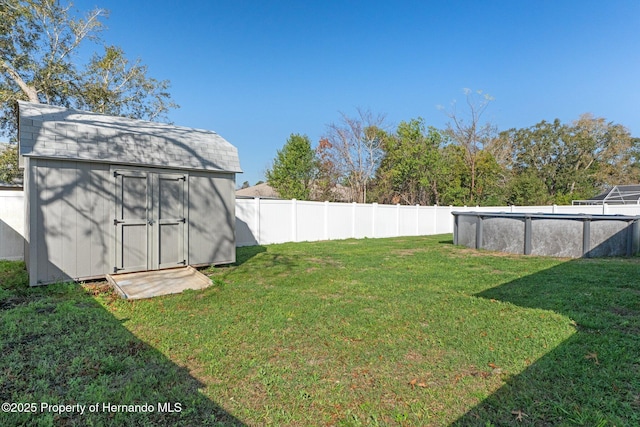 view of yard with a shed, an outdoor structure, a fenced backyard, and an outdoor pool