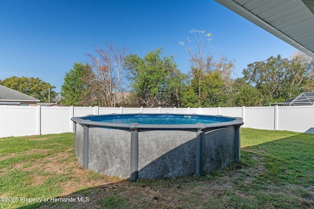 view of swimming pool with a fenced in pool, a fenced backyard, and a lawn