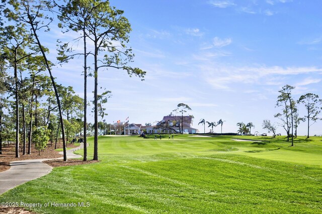 view of home's community with view of golf course and a lawn