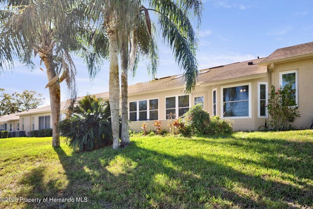 back of house featuring a lawn and stucco siding