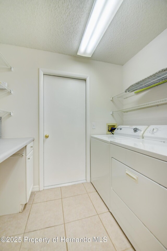 laundry area featuring washer and dryer, laundry area, light tile patterned flooring, and a textured ceiling