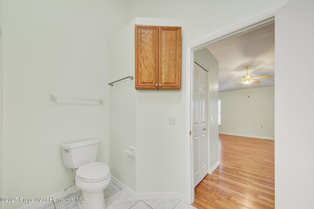 bathroom with baseboards, ceiling fan, toilet, and wood finished floors