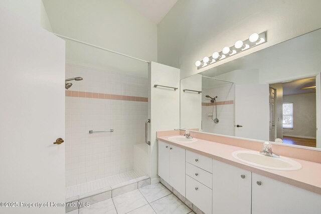 bathroom with double vanity, tiled shower, and a sink