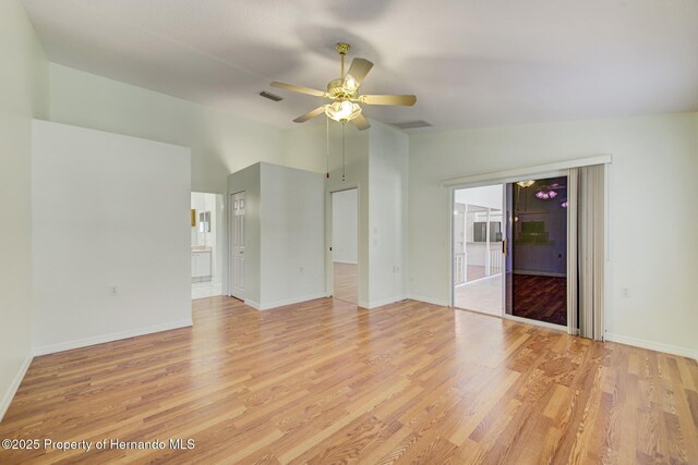 unfurnished room with vaulted ceiling, light wood finished floors, visible vents, and baseboards